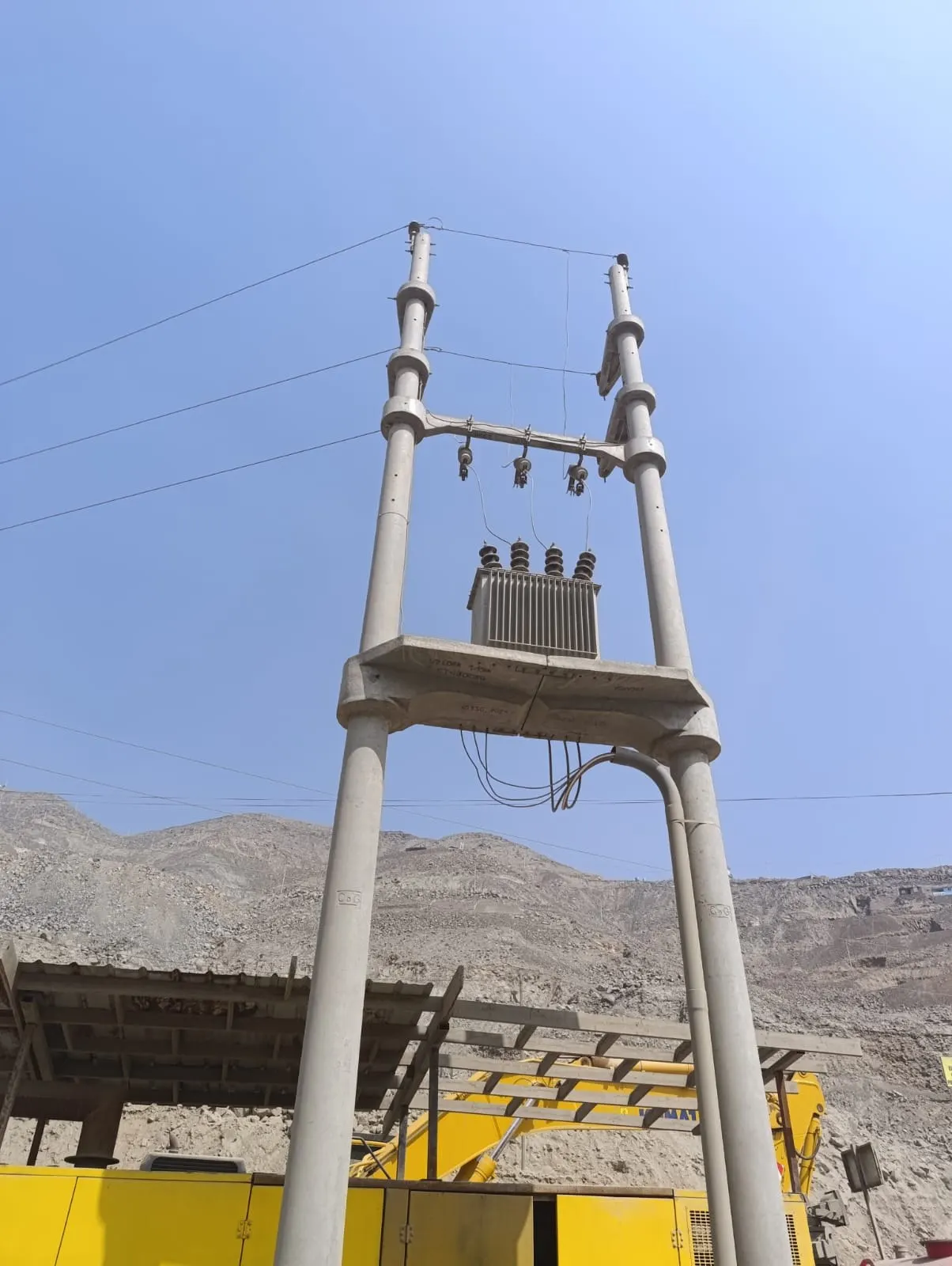 Subestación aérea con transformador montado sobre postes de concreto bajo un cielo despejado